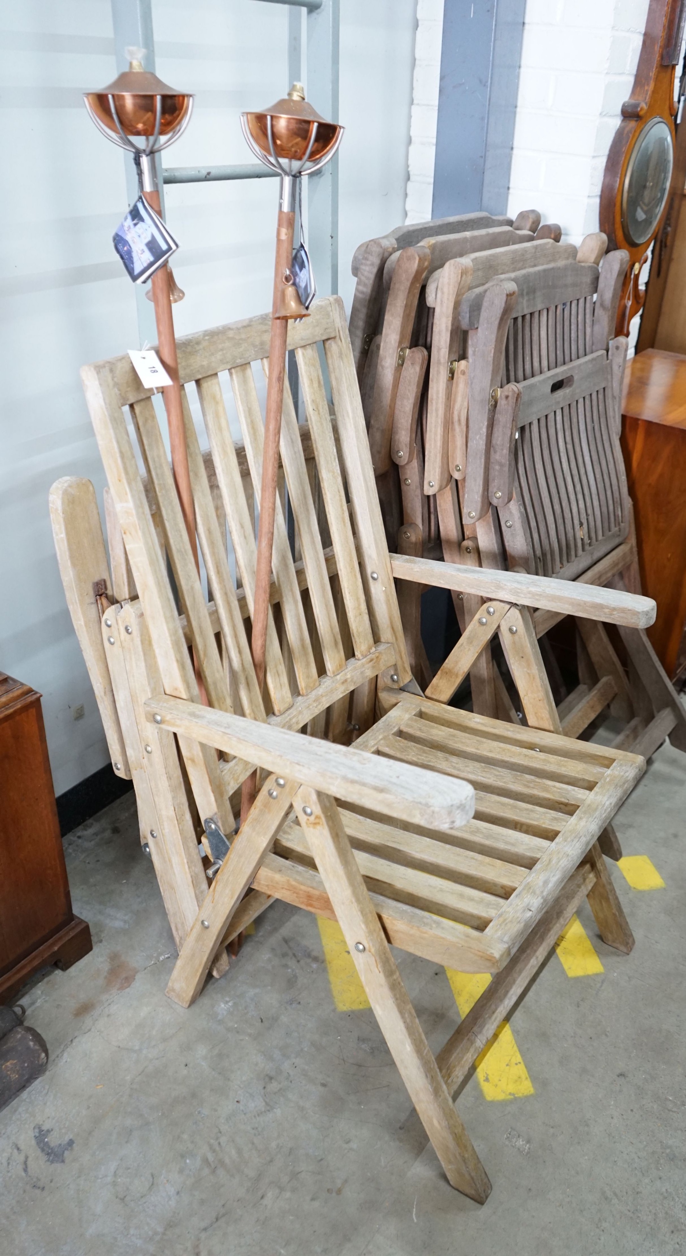 Four weathered teak folding garden chairs, a pair of teak reclining elbow chairs and a pair of Aristo garden oil lamps